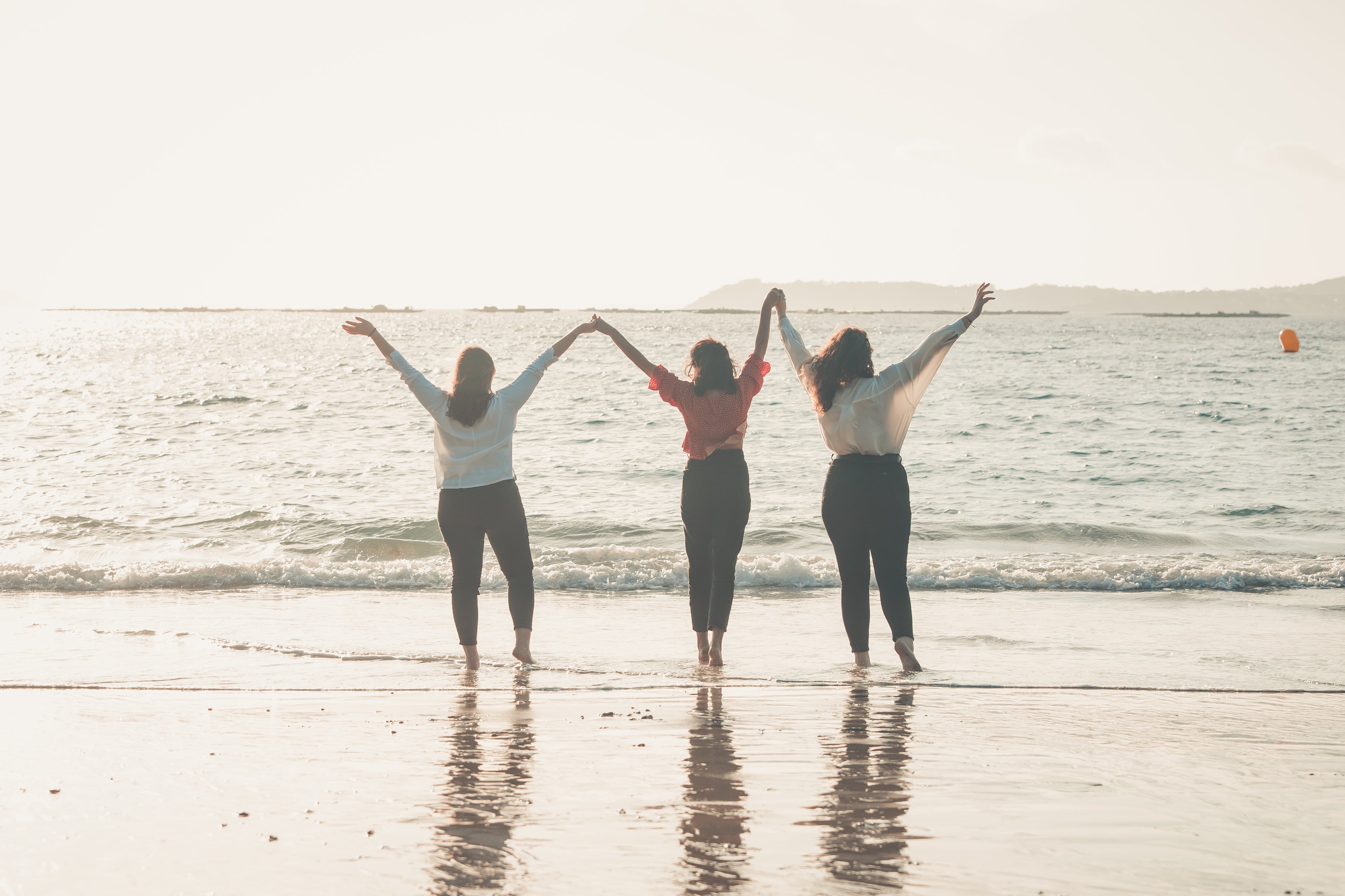 three-people-hold-hands-with-their-arms-to-the-sky